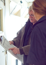 People looking at a barn chart hanging outside a door.